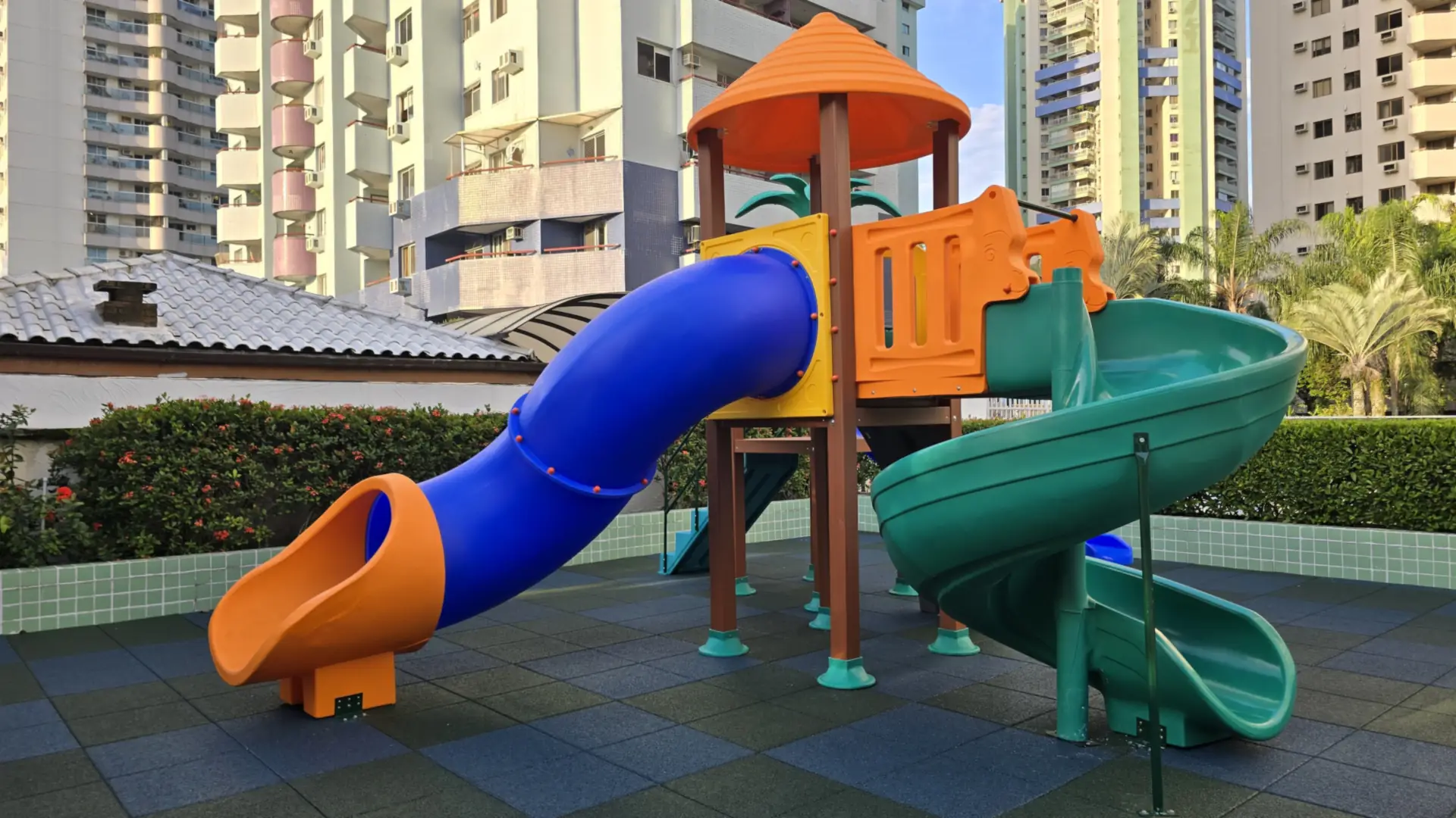 Playground com escorregador em tubo laranja e azul e escorregador espiral verde no Condomínio Keibiscane, Barra da Tijuca