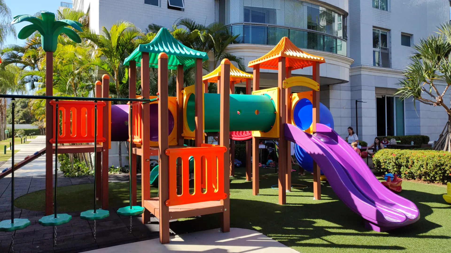 Playground com torres de telhados coloridos e escorregador roxo no Condomínio Mônaco, Barra da Tijuca