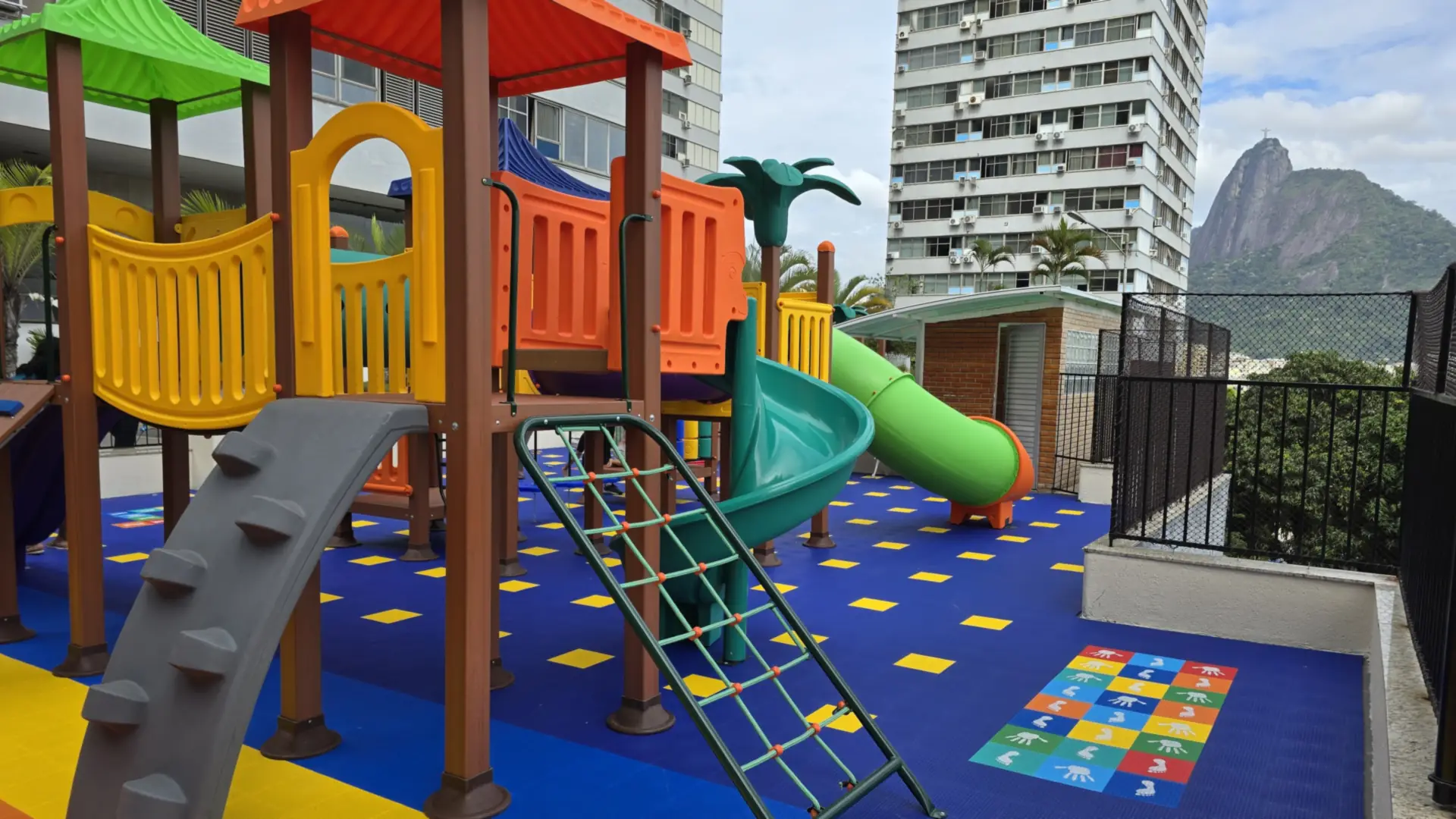 Playground sobre piso colorido no Condomínio Morada do Sol, em Botafogo, com o Pão de Açúcar ao fundo