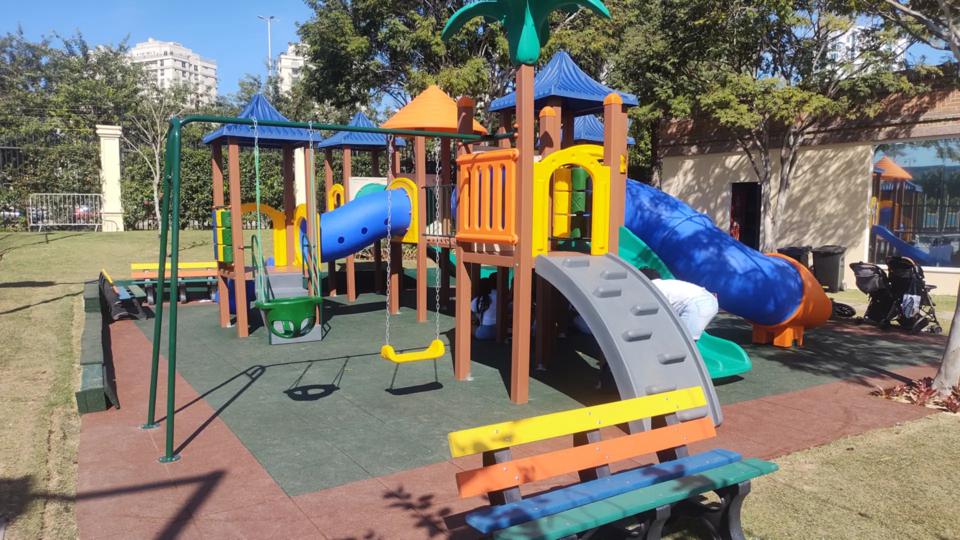 Playground com torres de telhados azul e laranja, balanços e escorregadores no Condomínio Santa Mônica, Barra da Tijuca