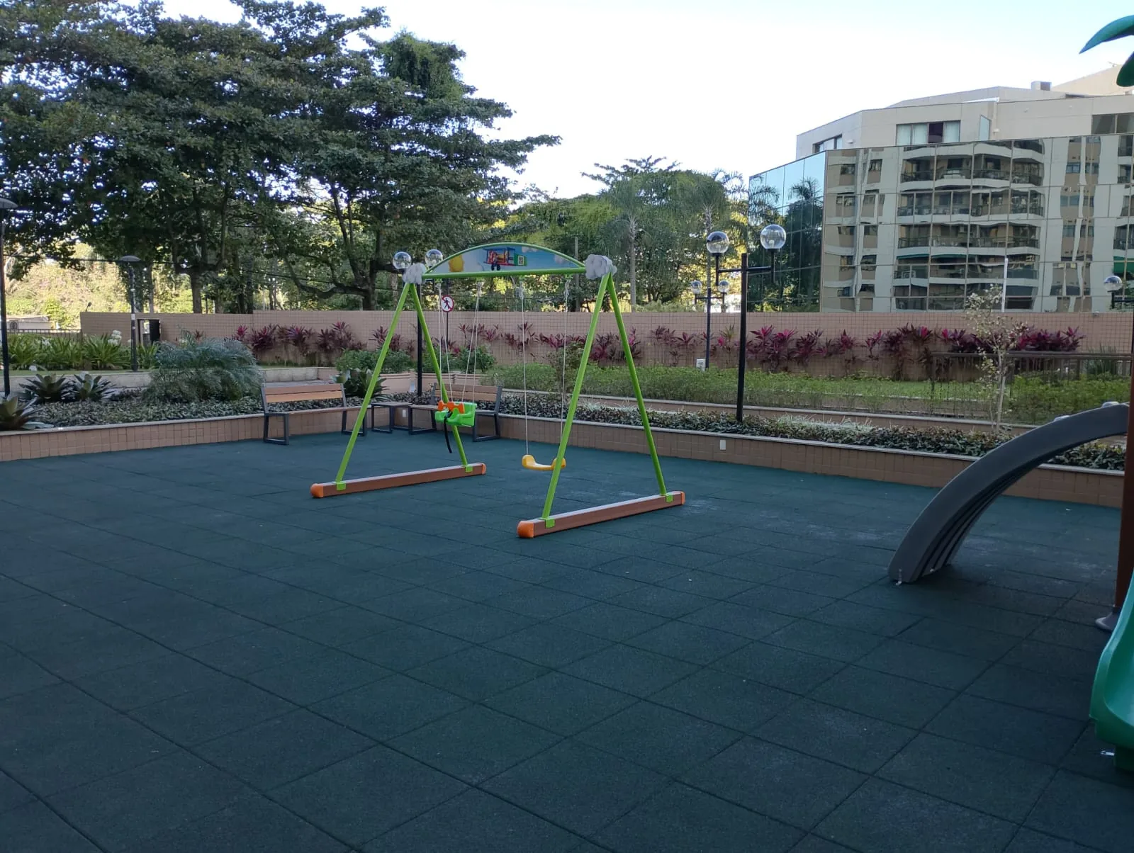 Balanço com assento de bebê e piso emborrachado cobrindo toda a área de lazer do condomínio