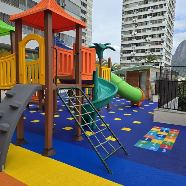 Playground sobre piso colorido no Condomínio Morada do Sol, Botafogo, com o Pão de Açúcar ao fundo